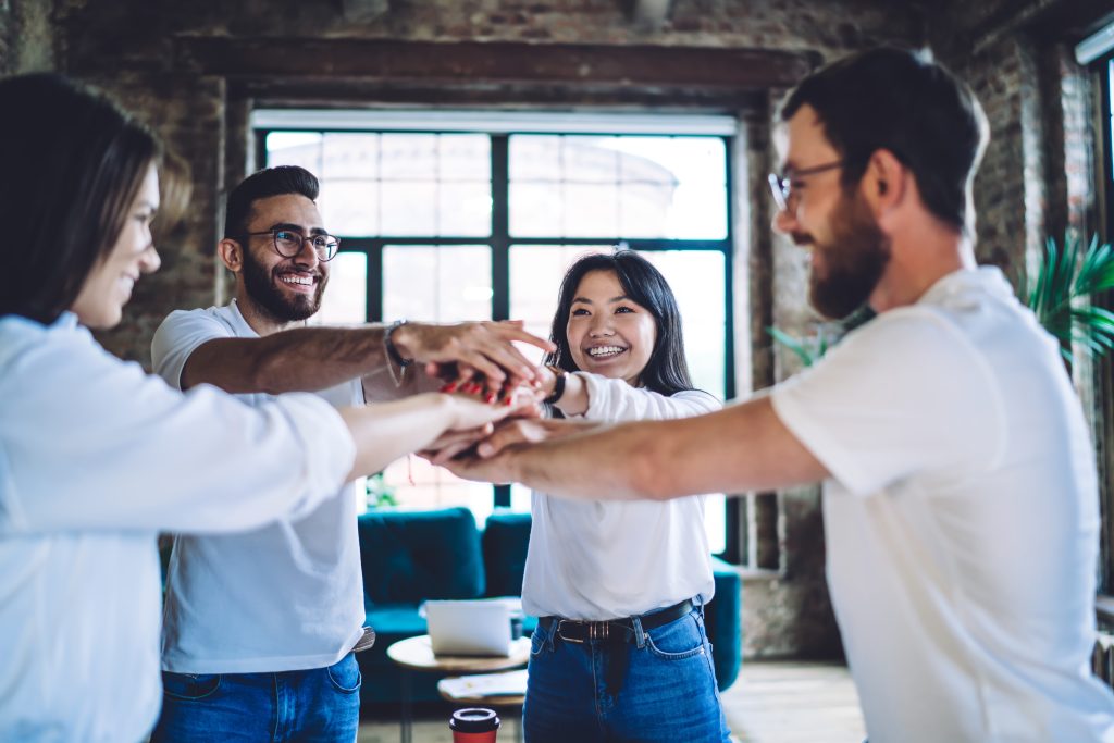 Happy colleagues stacking hands together in a workspace